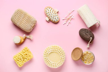 Masaj vücut fırçalarından yapılmış çerçeve, sünger taşı ve pembe arka planda banyo süngeri, yakın plan.