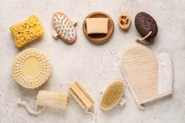 Masaj vücut fırçalarından yapılmış çerçeve, masaj eldiveni, süngerler ve beyaz grunge arka planda sabun çubuğu.