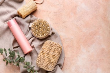 Kumaş, masaj vücut fırçası, süngerler ve pembe grunge arka planda bir şişe kozmetik ürünü, yakın plan.