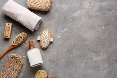 Gri grunge arka planda masaj vücut fırçaları, havlu ve bir şişe kozmetik ürünü ile kompozisyon