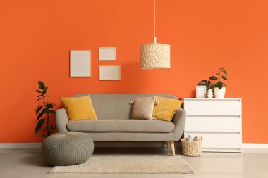 Çekmeceler, puf ve kanepe turuncu duvarın yanında oturma odasının iç tarafında.