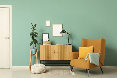 Çekmeceler, koltuk ve puf yeşil duvarın yanında oturma odasının iç tarafında.