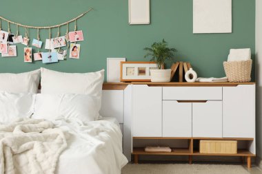 Yatak odasının içi. Yeşil duvarın yanında büyük, rahat bir yatak odası ve çekmeceler var.