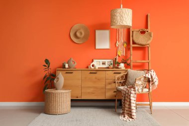 Çekmeceler, merdiven, koltuk ve oturma odasının içindeki turuncu duvarın yanındaki masa.