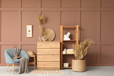 Çekmeceler, raf ünitesi ve oturma odasının iç tarafındaki kahverengi duvarın yanındaki koltuk.