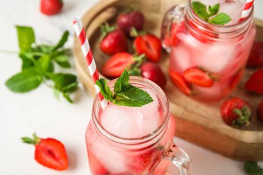 Beyaz arka planda çilekli lezzetli soğuk kokteyller, yakın plan.