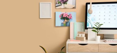 Bilgisayar monitörü, klavyesi ve bej duvarlı takvimi olan modern bir iş yeri. Tasarım için pankart