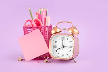 Leylak arka planında farklı kırtasiye malzemesi olan çalar saat