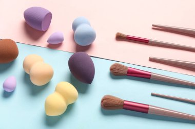 Renkli arkaplanda makyaj süngerleri ve fırçalar