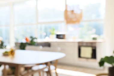 Açık mutfak, yemek masası ve tezgahlarla bulanık görünüyor.