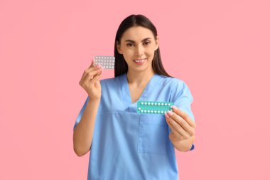 Pembe arka planda doğum kontrol hapları olan kadın jinekolog.