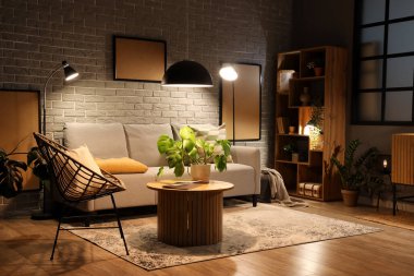 Gri kanepesi, ahşap sehpası ve akşam lambaları olan modern oturma odasının içinde.