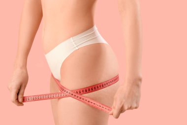 İç çamaşırlı, pembe arka planda mezurası olan güzel bir kadın. Selülit kavramı