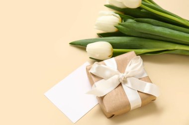 Hediye kutusu ve bej arka planda beyaz laleleri olan boş kart.