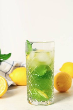 Limonlu bir bardak limonata ve beyaz arka planda nane şekeri.