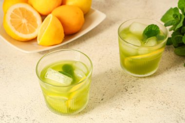 Nane aromalı lezzetli limonata ve beyaz arka planda limonlar.