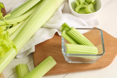 Beyaz ahşap arka planda taze yeşil kereviz kaseleri, yakın plan.