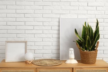 Beyaz tuğla duvarın yanındaki ahşap dolapta farklı bir dekor var.