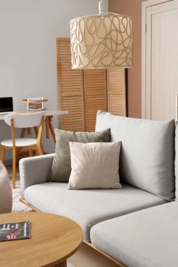 Gri kanepesi ve bej duvarın yanında ahşap sehpası olan şık bir oturma odası.