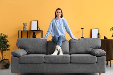 Aydınlık oturma odasındaki kanepede oturan genç kadın.