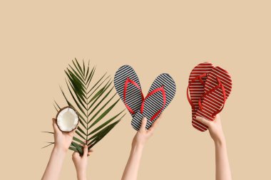 İki çift çizgili terlik, hindistan cevizi ve bej arka planda palmiye dalı tutan eller.