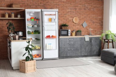 Mutfakta kahverengi tuğlalı arka planda taze ürünleri olan büyük modern buzdolabı.