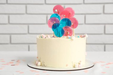 Beyaz tuğla duvara karşı masada doğum günü partisi için pasta.