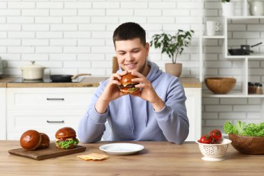 Mutfakta lezzetli burgeri olan genç bir adam.