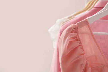 Pembe duvarın yanında asılı giysiler var.