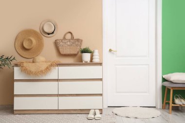 Hasır şapkalı sandıklar, hasır çanta ve koridorda saksılar.