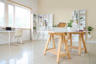 Çalışma alanları, dizüstü bilgisayarı ve raf ünitesi olan şık bir ofis.