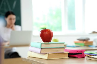 Sınıfta masa başında kitap ve kalem kutusu olan elma, yakın plan.
