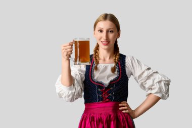 Gri arka planda bir kupa birayla güzel mutlu Ekim Festivali garsonu.