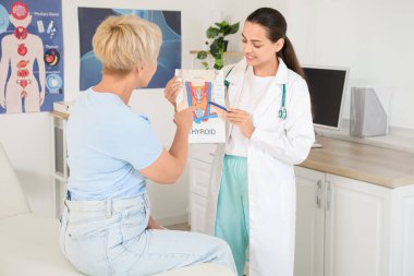 Tiroid bezinin yapısını klinikte olgun bir kadına gösteren kadın endokrinolog.