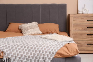 Yatak odasının içinde yastıkları ve çekmeceleri olan büyük, rahat bir yatak.