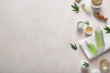 Beyaz arka planda toz ve yapraklarla kenevir kozmetik ürünleri şişeleri ve kavanozları