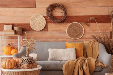 Oturma odasının sonbaharında rahat bir kanepe, ekose, balkabağı ve kahve masası.