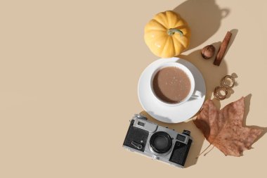 Bir fincan lezzetli balkabağı kahvesi, sonbahar süslemeleri, mücevherler ve sarı arka planda kamera.