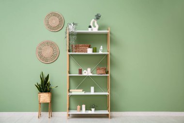 Odanın içinde raf ünitesi, bitkiler ve yanan mumlar var.