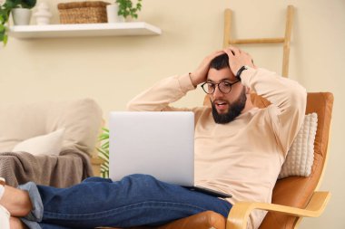 Evde dizüstü bilgisayarla çalışan stresli genç sakallı adam.