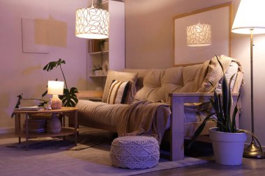 Rahat kanepesi, sehpası ve geceleri parlayan lambaları olan bir oturma odası.