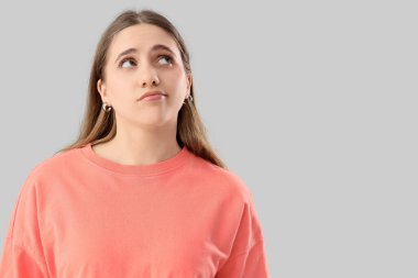 Gri arka planda düşünceli bir kadın.