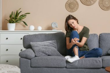 Oturma odasındaki kanepede oturan depresif genç kadın.