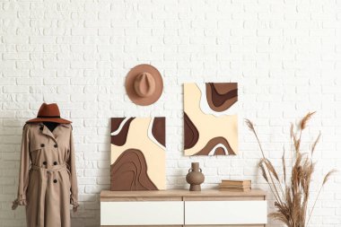 Çekmeceler, mankenler ve beyaz tuğla duvarın yanındaki tablolar.