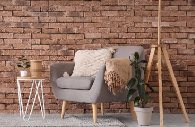 Gri koltuğu, masası ve bitkileri olan oturma odasının içinde.