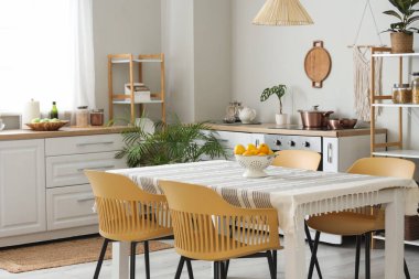 Mutfağın içinde tezgahlar, raf üniteleri ve yemek masası var.