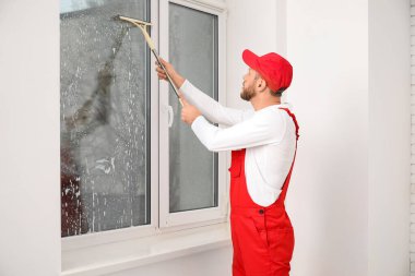 Odada cam sileceği olan erkek işçi.