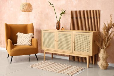 Koltuk, büfe, ekran ve vazodaki otlar oturma odasının içinde.