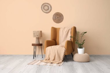 Kahverengi koltuk, puf ve masa, odanın içindeki bej duvarın yanında.