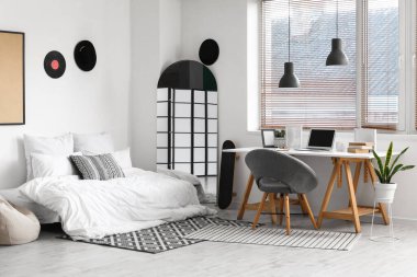 Yatağı, çalışma yeri ve aynası olan bir gencin odası.